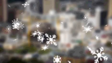 Multiple-snowflakes-icons-falling-against-aerial-view-of-blurred-cityscape