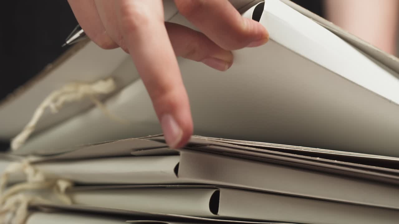 Detailní záběr ruky probírající stoh dokumentů s perem