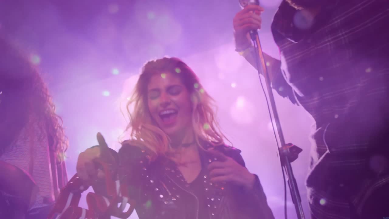 Cantante uomo che canta in un microfono con luci LED mentre la band suona il tamburello ed energizza la musica