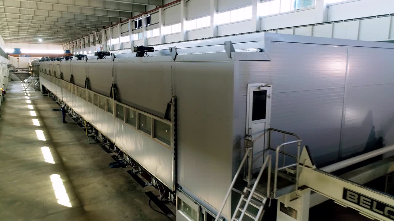 rollos de papel marrón en la línea de producción y trabajador en la planta