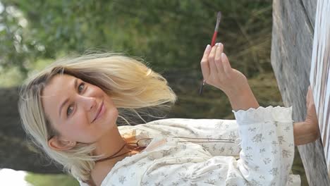 woman artist paints a picture in a summer park in sunlight hobby to paint pictures