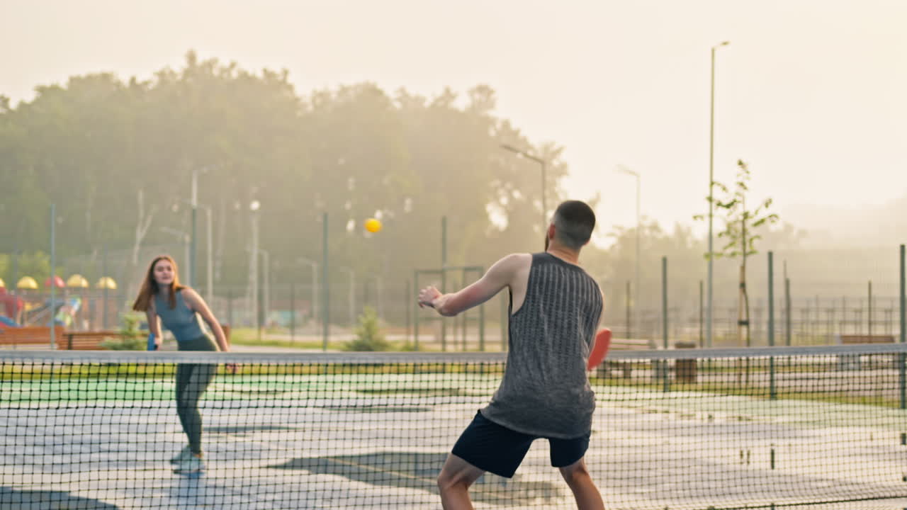A man and a woman playing pickleball after rain