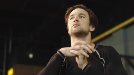 Stressed-male-boxer-preparing-for-fight-at-gym.-Male-athlete-warming-up-wrists