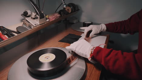 A-man-with-white-gloves-working-at-a-film-studio-examines-a-film-on-special-analog-equipment