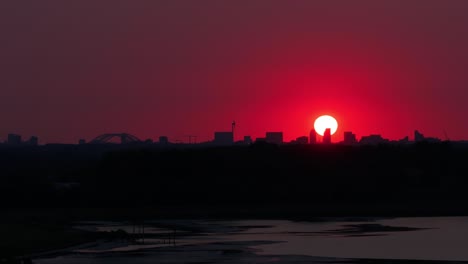 sun falls into the red skyline above rotterdam city