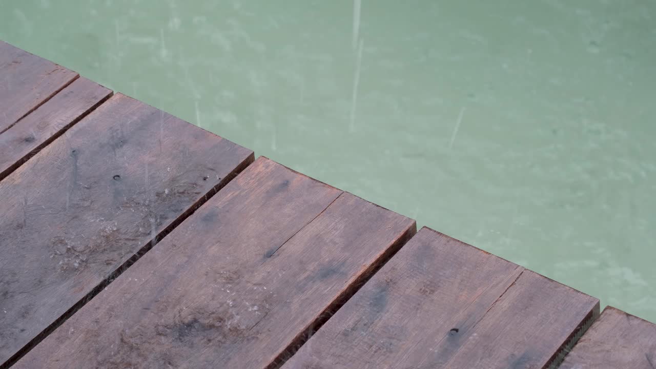 cerca de las tablas de madera del muelle del muelle con un vistazo del agua del océano y las gotas de lluvia que caen durante la tormenta de mal tiempo y la lluvia torrencial en el destino tropical