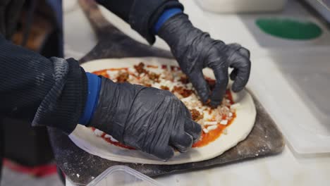 Close-up-of-chef-preparing-pizza-for-cooking,-adding-tuna-topping,-interior