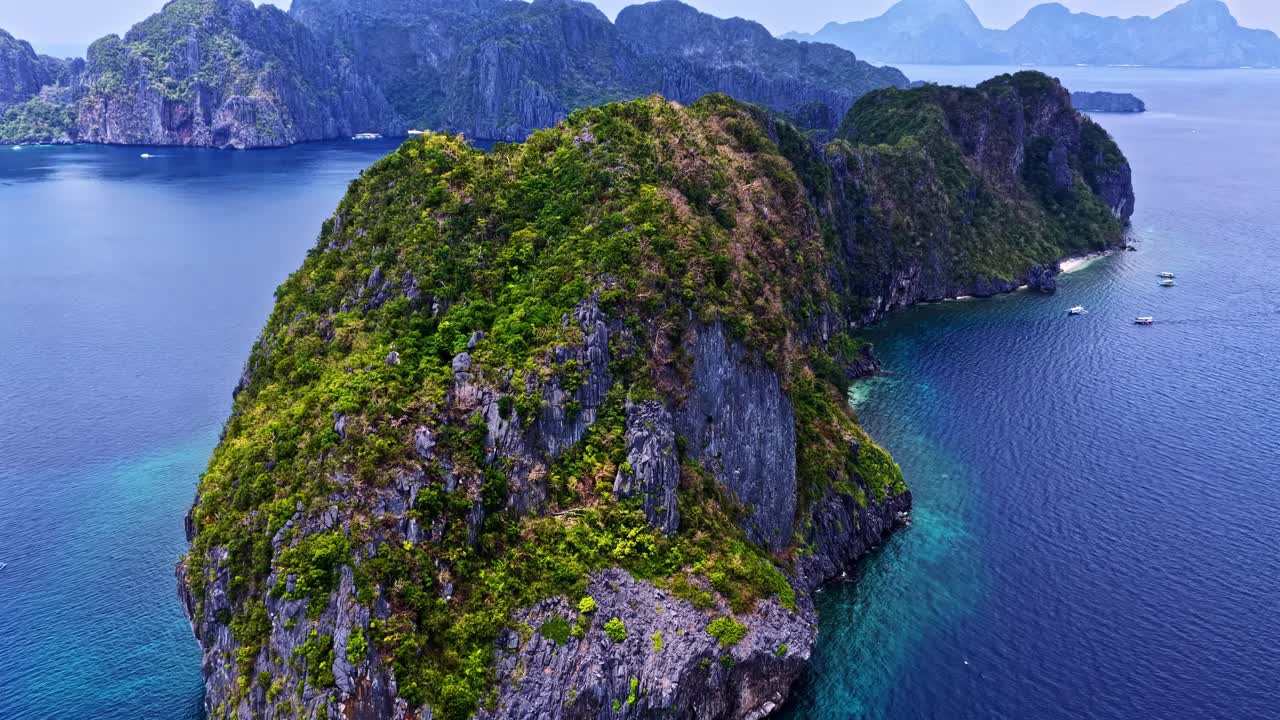 Veduta aerea con drone dall'alto delle montagne rocciose ricoperte di vegetazione nell'acqua, presso la spiaggia di El Nido nelle Filippine.