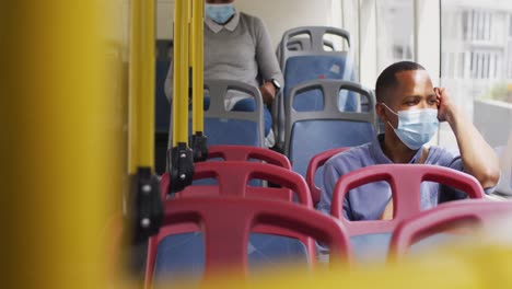 African-american-man-with-face-mask-sitting-in-bus