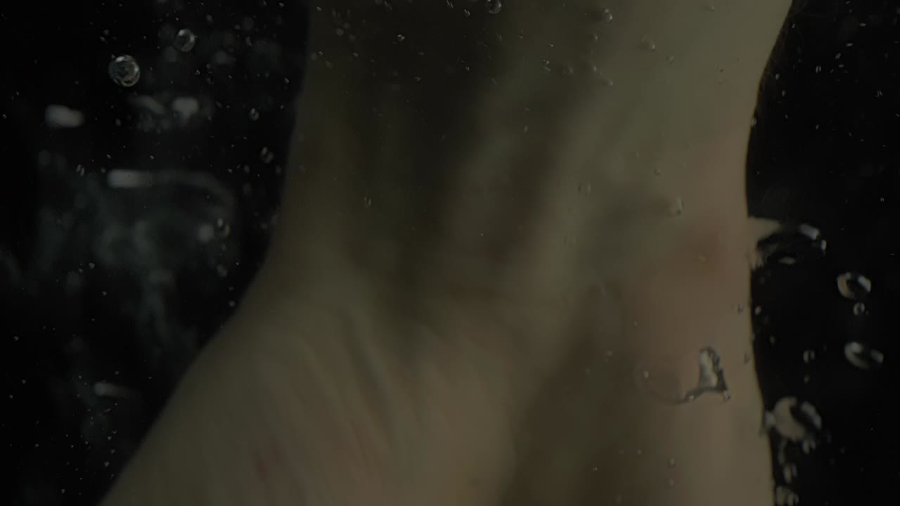 거품이 있는 물속에서 백인 인간의 손을 떨어뜨리고, 총을 닫습니다.