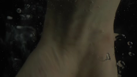 caucasian human dropping hand under water with bubbles,close up shot