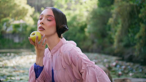 modelo de fantasía sensual posando en el lago del bosque sosteniendo una manzana de cerca. niña hada