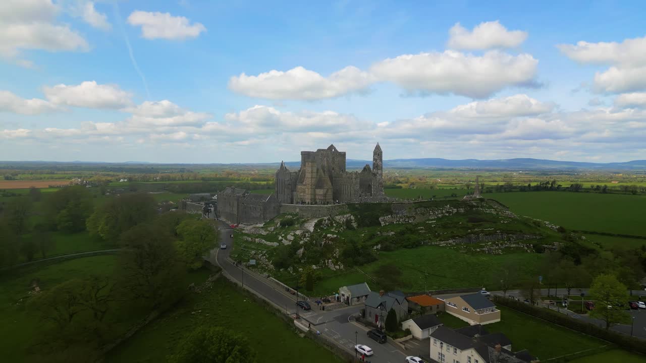 4K Aerial view of the Rock of Cashel, capturing ancient stone walls, round towers, and cathedral ruins surrounded by rolling green fields and historic farmland. Co.Tipperary, Ireland_0112