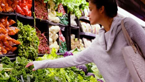 woman buying leafy vegetables in organic section