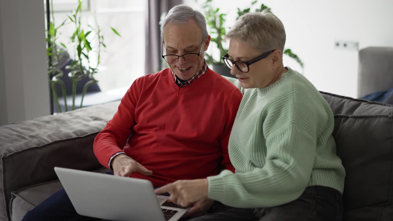Mature couple looking at laptop, discussing news
