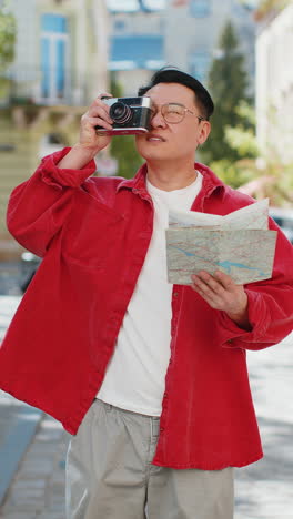 asian man tourist traveling on weekends exploring town looking city map, making photo pictures