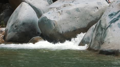 slow-motion shot of foamy water flowing through big rocks in a river in the forest