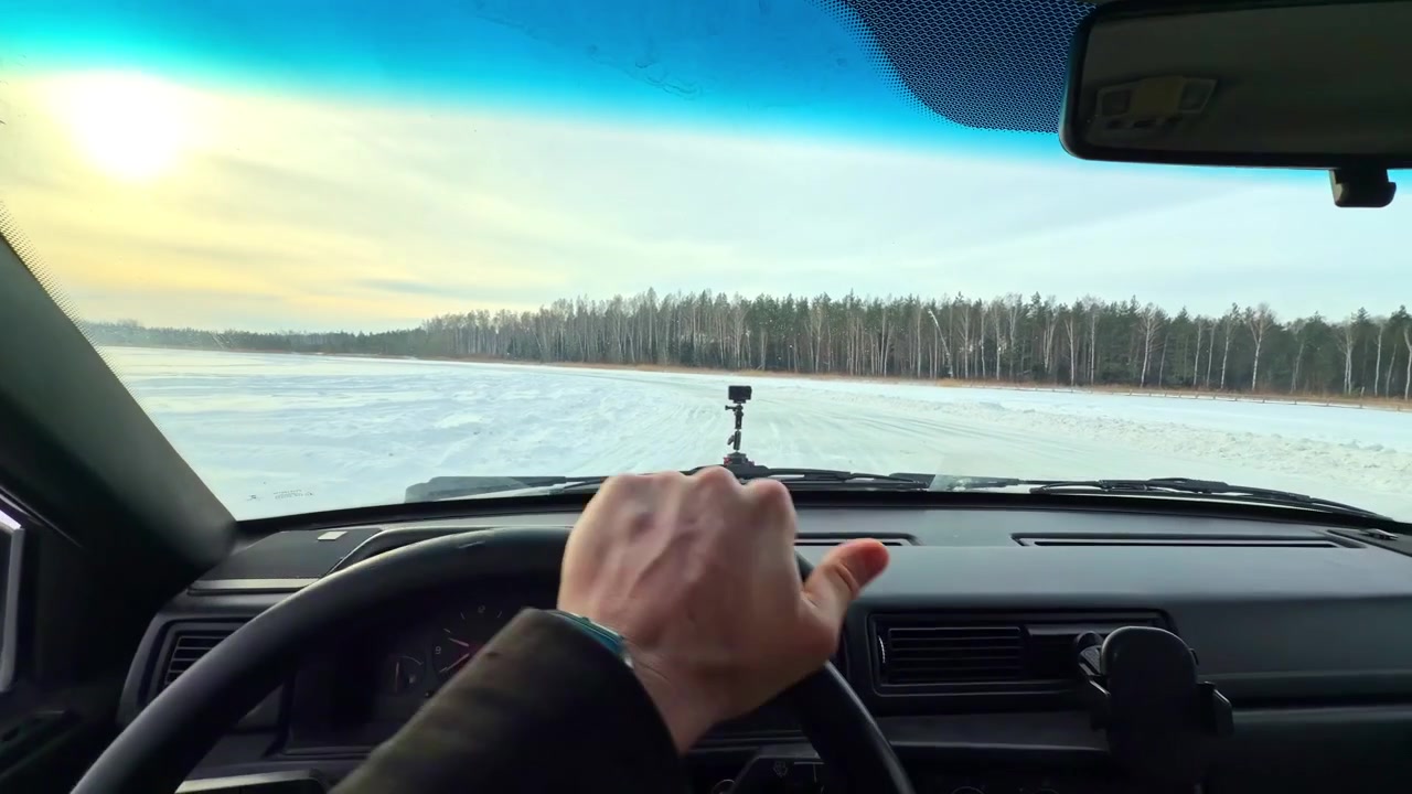 Driver's point of view driving and drifting on snowy road across a frozen lake in winter