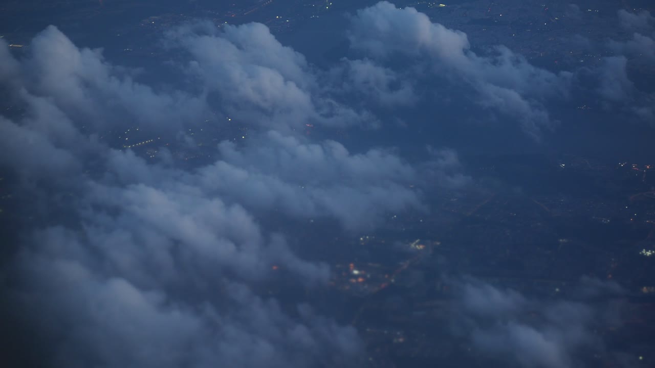 Aerial View of City Lights Through Clouds at Night