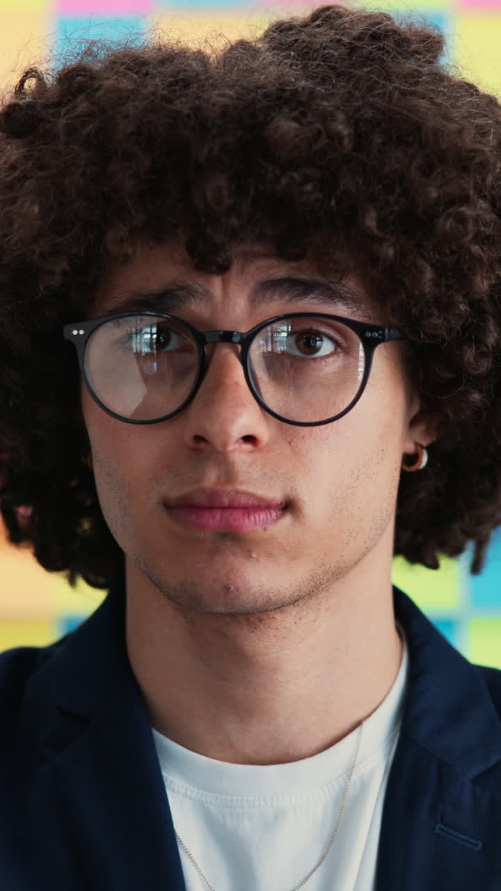 Close Up Portrait of a Thoughtful Young Man with Curly Hair and Glasses