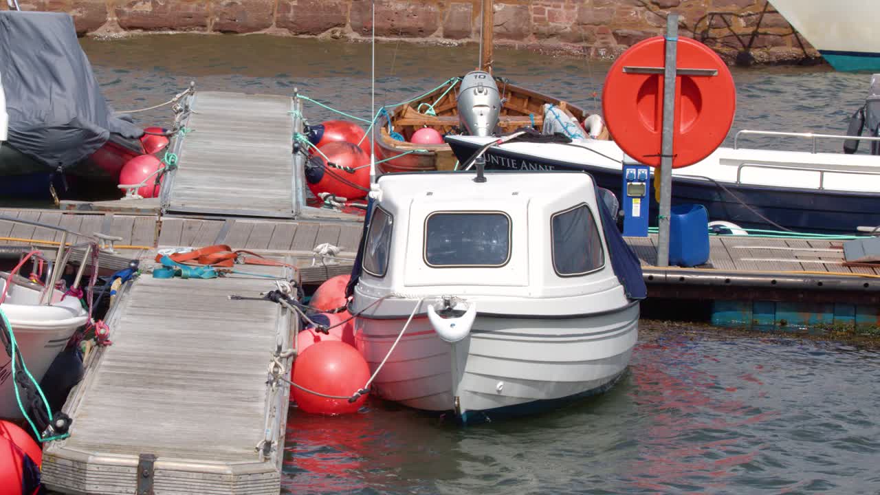 Moored boats sway against floating pontoon, choppy water, overcast daylight, handheld camera movement
