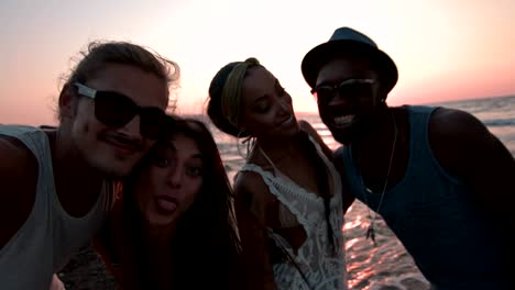 amigos multiétnicos divirtiéndose tomando selfies en la playa al atardecer