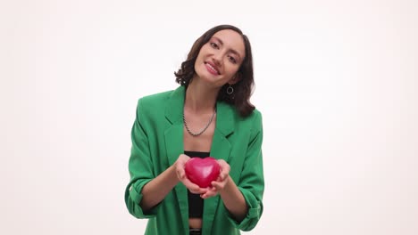smiling woman in green jacket holding a red heart