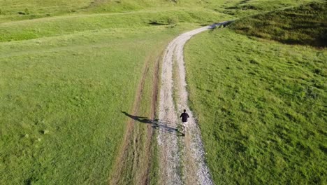 Luftaufnahmen-Eines-Mannes,-Der-An-Einem-Sonnigen-Sommertag-Sein-Fahrrad-Auf-Einer-Landstraße-Reitet