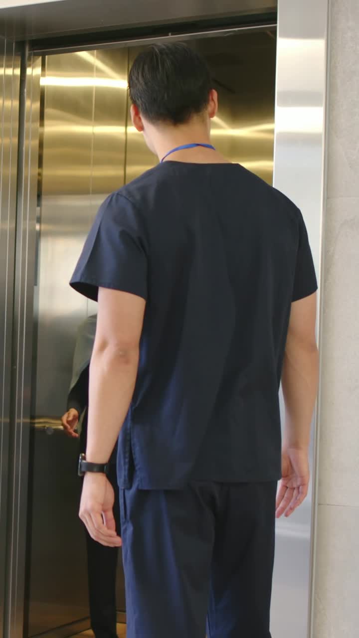 Video vertical: Personal de la clínica con uniforme quirúrgico presionando el botón del ascensor, sujetando la puerta, gesticulando y mostrando una tablet.