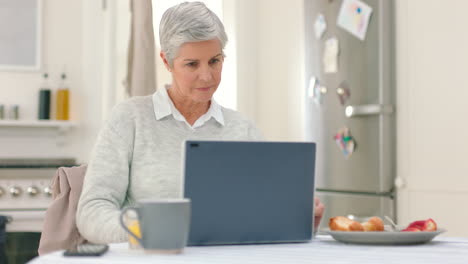 Laptop,-phone-and-breakfast-with-a-senior-woman