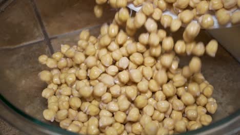 verter garbanzos o garbanzos lavados y empapados en un tazón de vidrio, cámara lenta superior