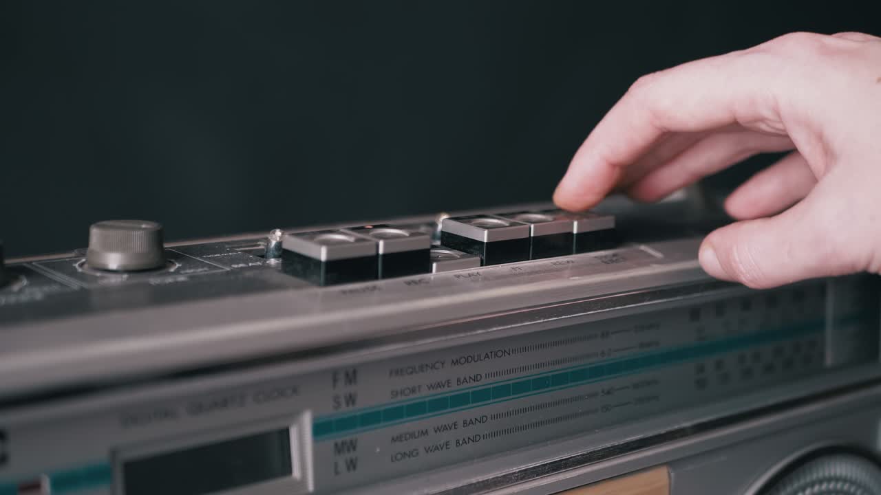 dedos femeninos presionando botones en una vieja grabadora de cinta vintage en una habitación oscura