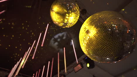 still upward motion clip of yellow disco balls hanging at wedding party, with strobe light reflections and led strips hanging as well.