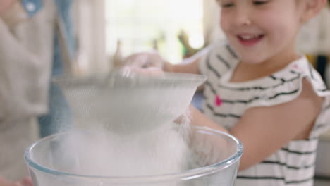 Glückliches-Kleines-Mädchen-Hilft-Mutter-Beim-Backen-In-Der-Küche,-Mischt-Zutaten,-Sieben-Mehl-Mit-Einem-Sieb-Und-Bereitet-Zu-Hause-Ein-Rezept-Für-Cupcakes-Vor