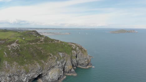 drone footage showing large mountain with people trekking and island on the background on a blue sea ocean on a brigh sunny day