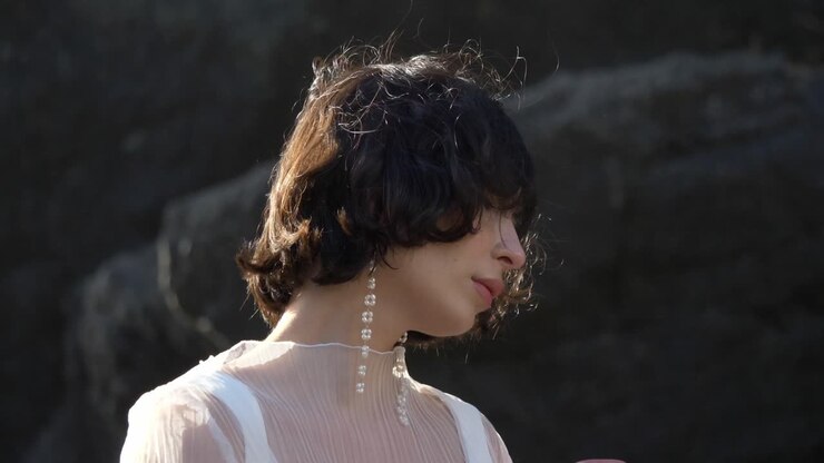Ritratto di una donna elegante che posa all'aperto in un paesaggio naturale.
