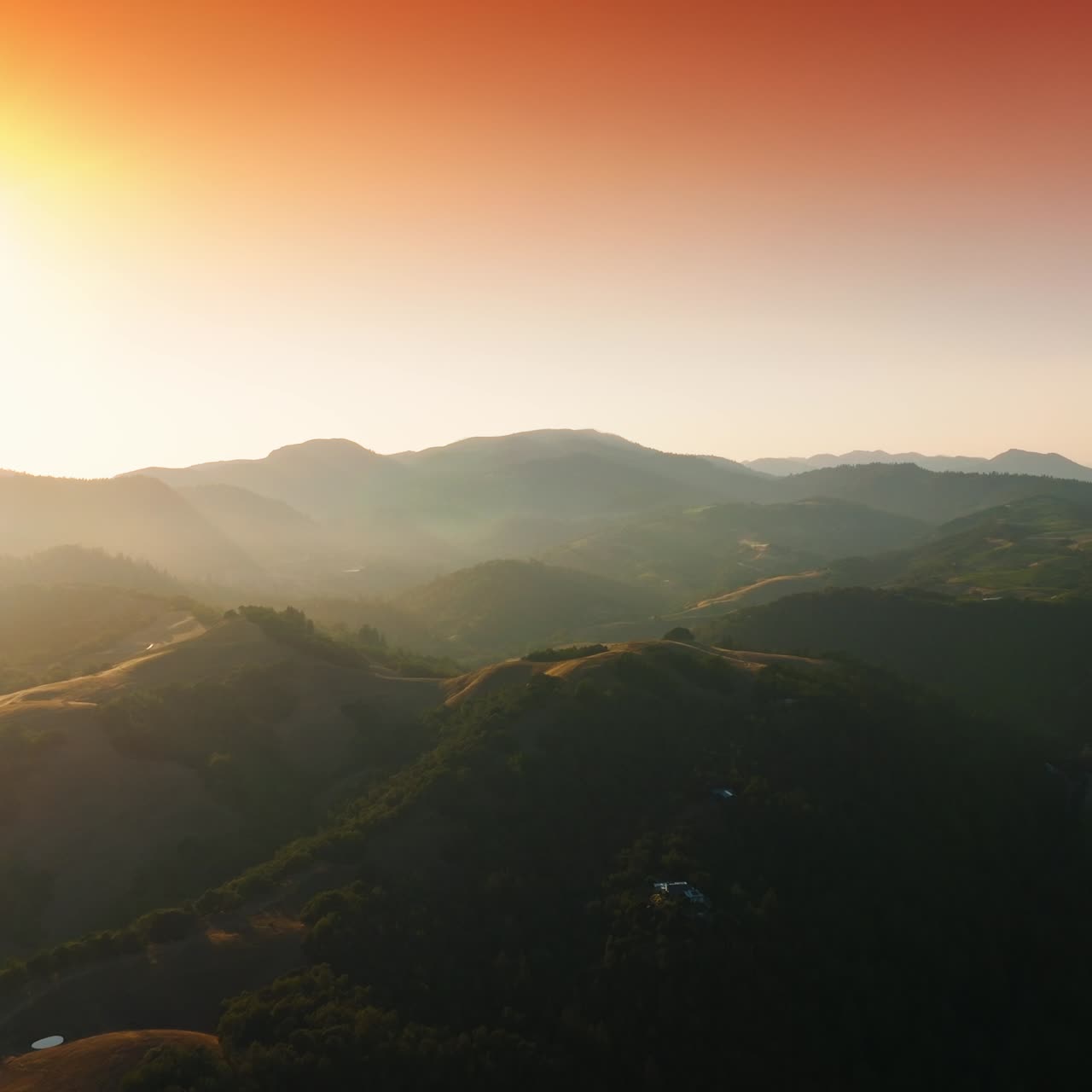 Beautiful green hills covered with vineyards. Picturesque rocky landscape in the rays of setting sun. Pink sky at backdrop