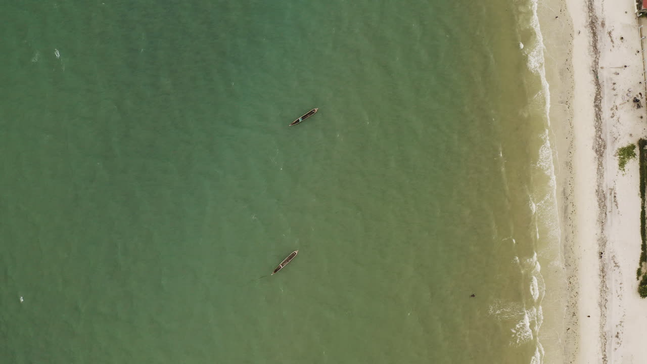 toma aérea de dos canoas de madera ancladas cerca de la costa de la playa en dar es salaam, tanzania