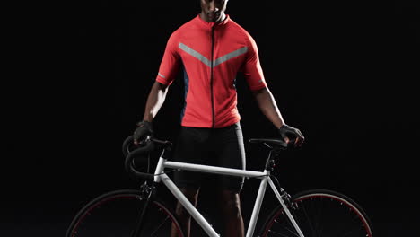 african american cyclist stands with his road bike on a black background