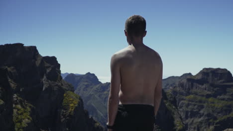 pulling away from man standing on dramatic mountain overlook, slow motion