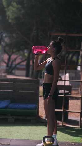 young woman drinking water after outdoor workout