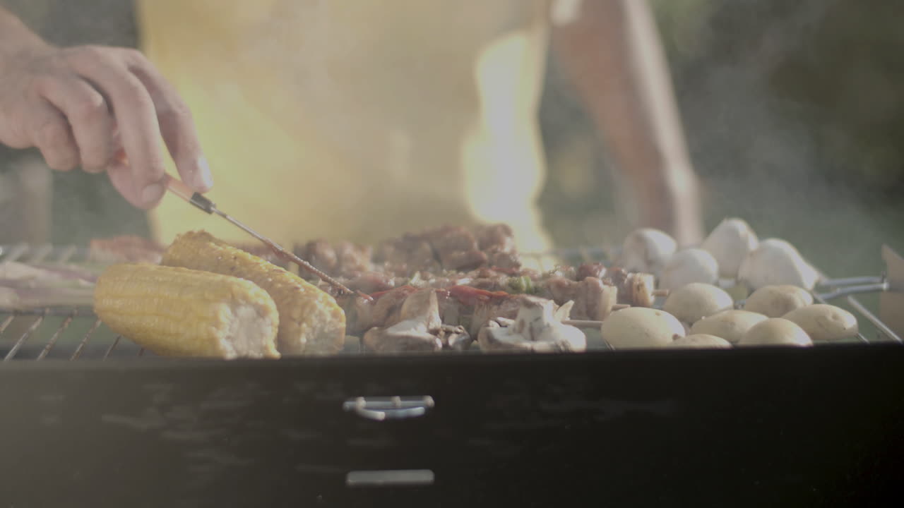 바베큐 그릴 에 고기 위 에 케치업 을 뿌리는 사람 의 클로즈업