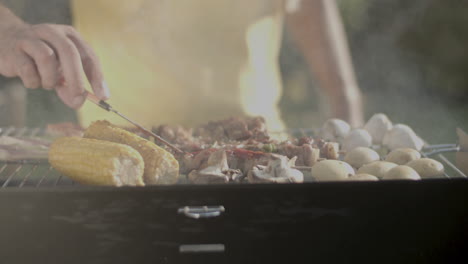 primer plano de un hombre extendiendo ketchup sobre la carne en la parrilla de barbacoa