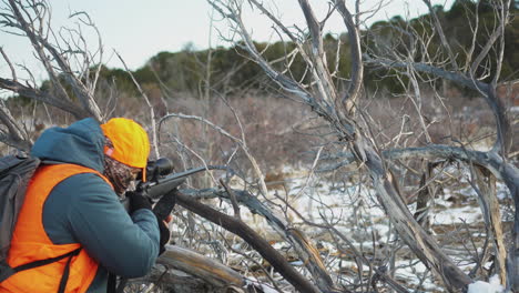 the hunter is carrying a rifle and aiming at the target of the game in the wild in winter