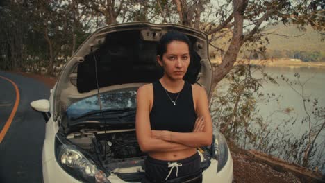 woman with broken down car by lake