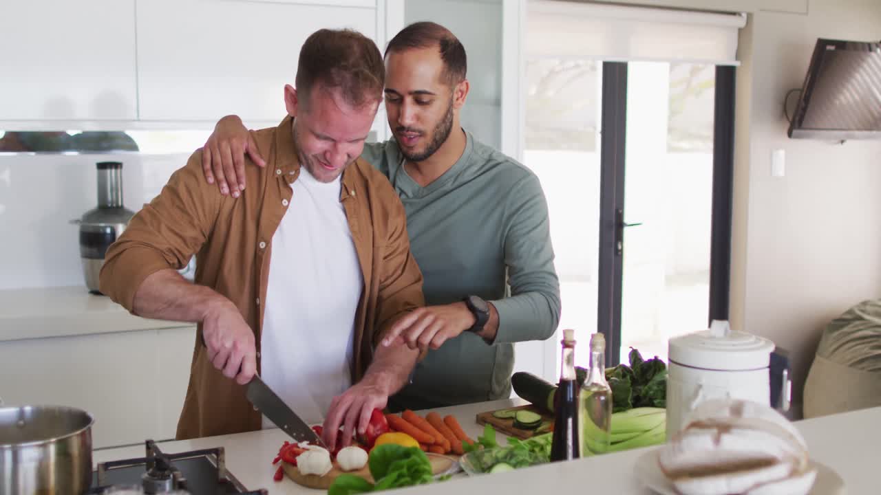 Multiethnisches schwules Paar bereitet Essen zu und unterhält sich in der Küche.