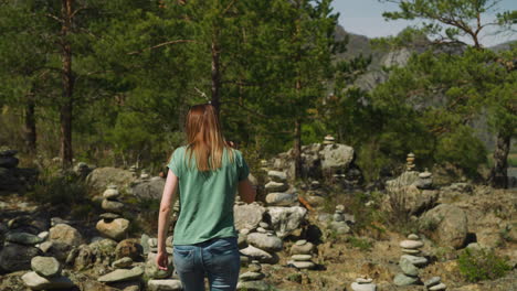 mujer camina entre simbólicas pilas de piedra vieja cerca del bosque de abeto