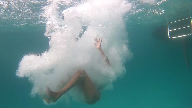 Girl jumps into the water from a yacht, slow motion underwater viewing