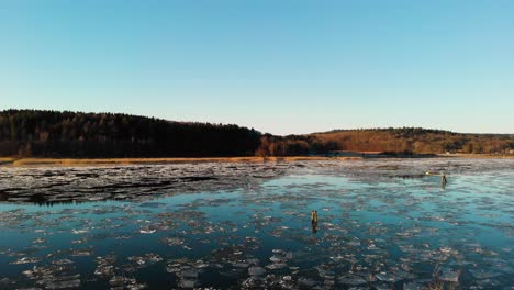 Rising-Aerial-Shot-Of-A-Beautiful-Lake-Covered-In-Melting-Ice-At-Sunrise-In-Gothenburg,-Sweden