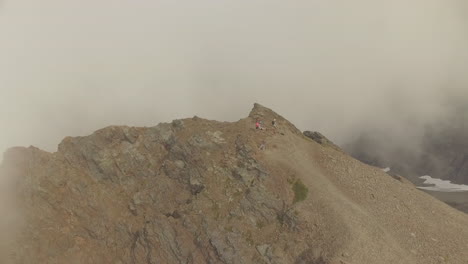 Eine-Drohne-Kreist-Um-Einige-Wanderer,-Die-Nach-Dem-Erreichen-Eines-Berggipfels-Eine-Pause-Machen